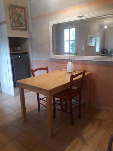 uma mesa de madeira e cadeiras numa cozinha com uma janela em La maison du jardin em Rustrel