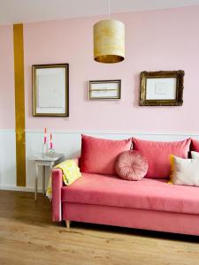 um sofá rosa com almofadas num quarto em Gallery Apartment Bielefeld em Bielefeld
