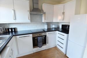 a kitchen with white cabinets and a stove top oven at Luxury 2 BR Fully Furnished Flat in Crawley - 2 FREE Parking Spaces in Crawley