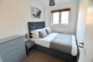 a bedroom with a bed and a dresser and a window at Luxury 2 BR Fully Furnished Flat in Crawley - 2 FREE Parking Spaces in Crawley