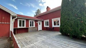 una casa roja con una terraza de madera delante de ella en Strandvägen 4, en Järvsö