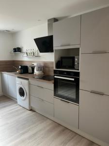 a white kitchen with a stove and a microwave at Le Vox - appartement de centre-ville in Montélimar