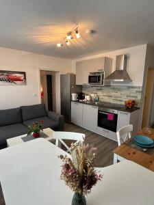 a living room with a white table and a kitchen at Schubart Apartments in Bietigheim-Bissingen