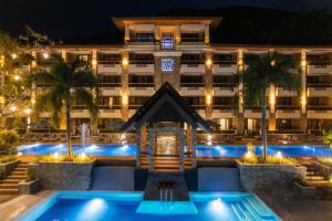 a hotel with a swimming pool at night at Coron Westown Resort in Coron