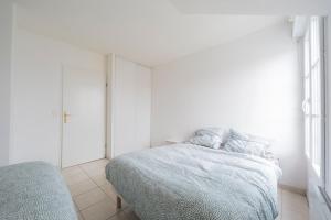 a white bedroom with a bed and a mirror at PARIS/DISNEY 50m2 +Balcon Paris’land Appartement in Bussy-Saint-Georges
