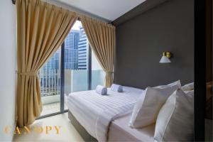 une chambre avec un lit et une grande fenêtre dans l'établissement The Luxe & The Colony, KLCC, à Kuala Lumpur