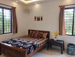 een slaapkamer met een bed en 2 ramen bij SHI's Vagamon Hill Retreat- Private villa on Hills in Vagamon