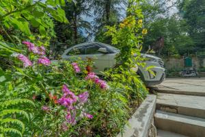 a car parked in a parking lot with flowers at Hotel Negi's Mayflower A heritage Since 1965 in Manāli