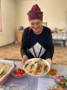 a man holding a bowl of food on a table at Handicraft house in Karakol