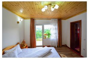 a bedroom with a bed with a wooden ceiling and a window at Pensiunea 7 Brazi in Poiana Mărului