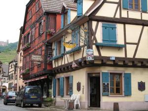 un bâtiment dans une rue avec une voiture garée devant dans l'établissement Le Bretzel, à Ribeauvillé