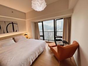 a bedroom with a bed and a chair and a window at Manriver Executive Apartments in Guangzhou