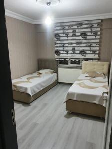 Habitación con 2 camas y pared con botellas de vino. en Mükemmel Konum'da Lüx Dairede Konaklama, en Sivas