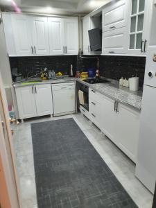 a kitchen with white cabinets and a tile floor at Mükemmel Konum'da Lüx Dairede Konaklama in Sivas
