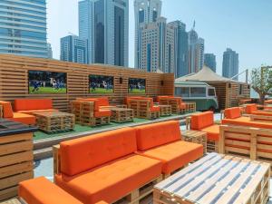 un restaurante con mesas y sillas naranjas y una ciudad en Hilton Doha, en Doha