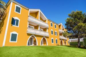 un gran edificio naranja con un césped verde delante de él en Vibra Blanc Palace Aparthotel, en Sa Caleta