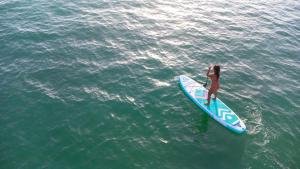 a woman standing on a surfboard in the water at Kampaoh Hostel El Palmar in El Palmar