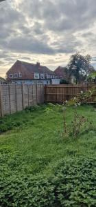 a yard with a wooden fence and a house at Ritzs place in Northolt