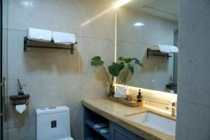 a bathroom with a sink and a mirror and a toilet at Manriver Executive Apartments in Guangzhou
