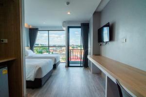 a hotel room with two beds and a balcony at Goodday Hotel in Ban Nong Waeng