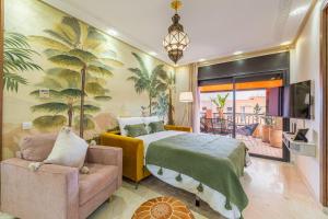 a bedroom with a bed and a couch and a tv at L'Atlas - Appartement Authentique à Gueliz in Marrakesh