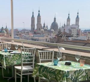 2 mesas con copas de vino en un balcón con vistas en Aparthotel Los Girasoles en Zaragoza