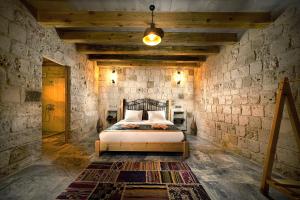 1 dormitorio con 1 cama en una pared de piedra en Caverna Hotel Premium Caves en Goreme