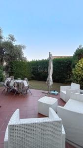 a patio with white chairs and a table and an umbrella at Casa con Giardino in Milazzo