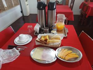 een rode tafel met een bord brood en sinaasappelsap bij Piratininga Guesthouse Casa de Hóspedes in Niterói