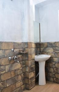 a bathroom with a white sink and a stone wall at SYLWAN-O SUNRISE HOMESTAY 