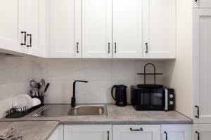 a kitchen with white cabinets and a sink and a microwave at Romari Vip Дорошенка 13 in Lviv