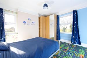 Schlafzimmer mit einem blauen Bett und Fenstern in der Unterkunft Equestrian Idyllic Victorian Retreat 