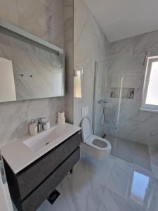 a white bathroom with a sink and a toilet at Apartments Filipo in Trogir