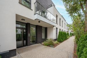 a white building with glass doors and a sidewalk at Royal Wilanów Comfort Apartment in Warsaw