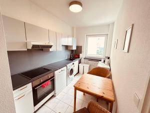 cocina con armarios blancos, mesa y fogones en Cozy Apartment close to Hamburg, en Reinbek