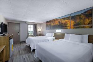 a hotel room with two beds and a flat screen tv at Days Inn by Wyndham Lincolnton in Lincolnton