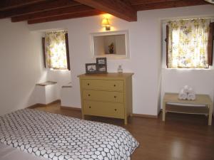 a bedroom with a bed and a dresser and two windows at Casa do Castelo - Coroa in Castelo de Vide