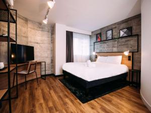 Dormitorio con cama, escritorio y TV en ibis Belfast City Centre, en Belfast