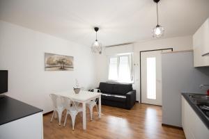 cocina y sala de estar con mesa blanca y sillas en Appartamento Patrizia, en Altavilla Vicentina