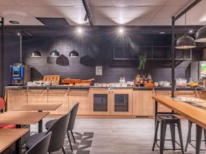 a kitchen with wooden cabinets and tables and chairs at ibis Nantes Treillières in Treillières
