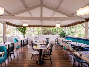 ibis Styles Quimper في كامبار: غرفة طعام مع طاولات وكراسي ونوافذ