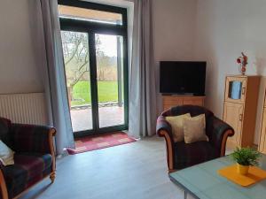 ein Wohnzimmer mit 2 Stühlen, einem Tisch und einem TV in der Unterkunft Ferienwohnungen direkt am See in Ventschow