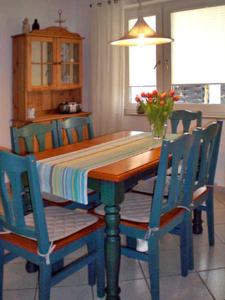 einem Esstisch mit blauen Stühlen und einem Tisch mit Blumen in der Unterkunft Ferienwohnung Paul in der Rostocker Heide in Blankenhagen