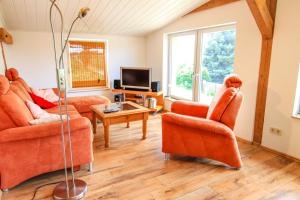 a living room with orange chairs and a tv at Reit- und Ferienhof Nieder Voddow in Rubenow