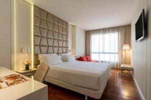 a hotel room with a large white bed and a window at NH Collection Barcelona Podium in Barcelona