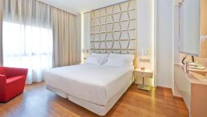 a bedroom with a white bed and a red chair at NH Collection Barcelona Podium in Barcelona