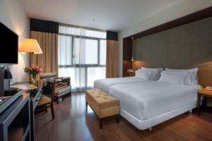 a hotel room with a large bed and a desk at NH Collection Sevilla in Seville