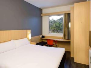 a bedroom with a large white bed and a window at ibis Manaus Aeroporto in Manaus