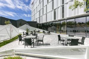 um grupo de mesas e cadeiras em frente a um edifício em Hampton By Hilton Alcobendas Madrid em Alcobendas