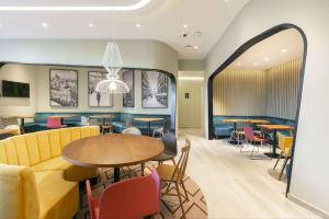 uma sala de jantar com mesas e cadeiras e um sofá em Hampton By Hilton Alcobendas Madrid em Alcobendas